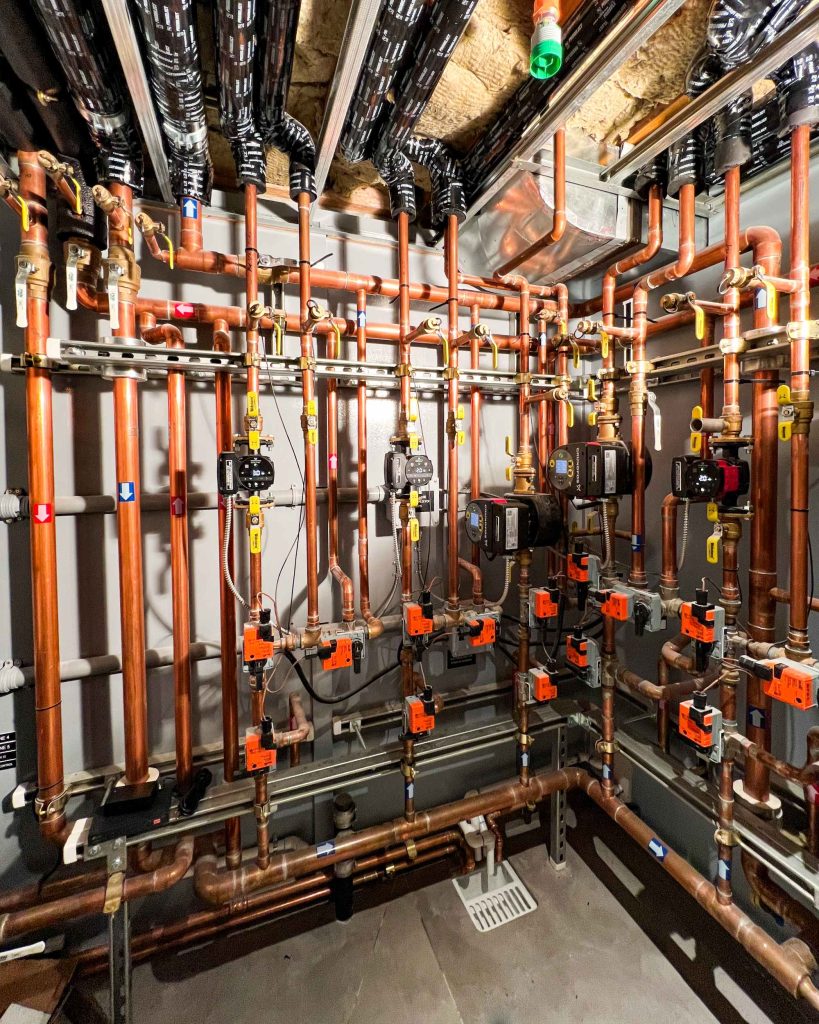 Complex mechanical room used to provide hydronic radiant cooling and heating via geothermal heat pumps.